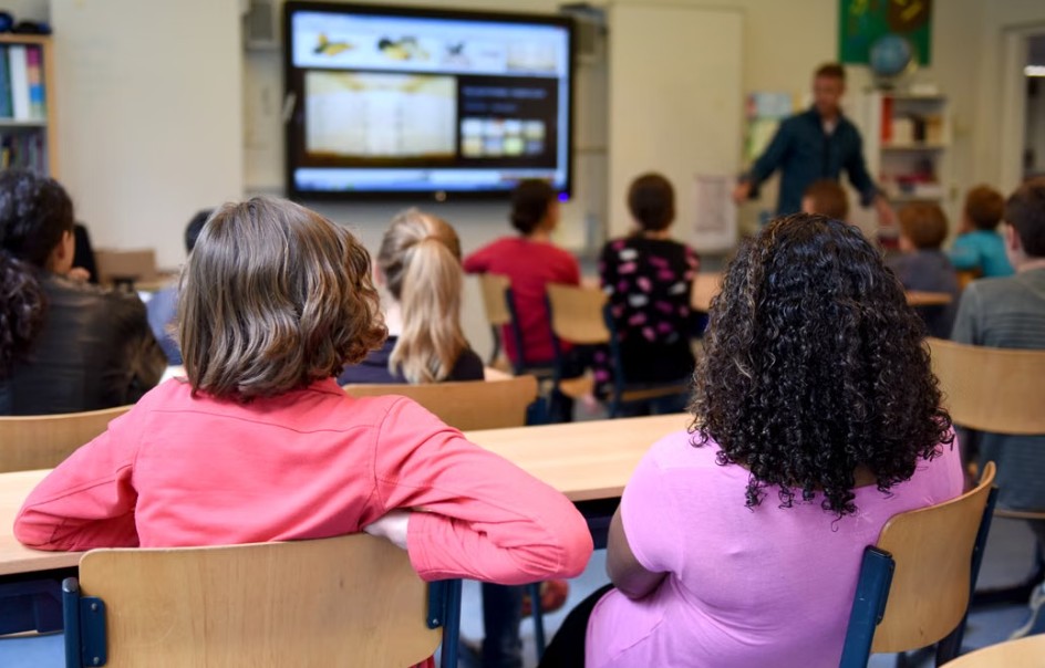Estudiantes recibiendo una lección interactiva con apoyo tecnológico en Centro Educativo Nuevos Horizontes.